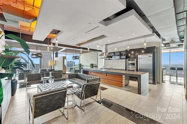 kitchen with floor to ceiling windows, tasteful backsplash, island range hood, pendant lighting, and stainless steel appliances