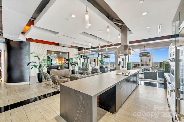 kitchen featuring cooktop, a wall of windows, a large island, and pendant lighting