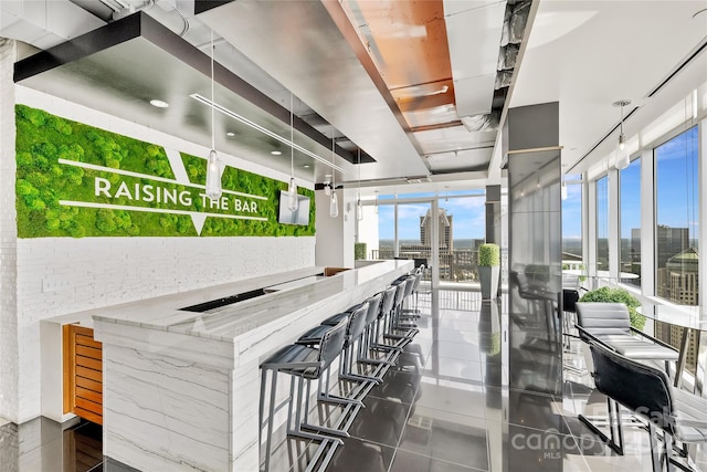 bar with decorative light fixtures and light stone countertops