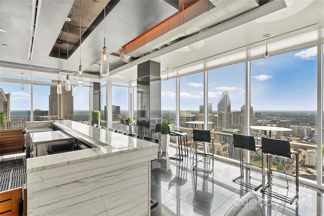 kitchen featuring floor to ceiling windows, pendant lighting, light stone countertops, and light tile patterned floors