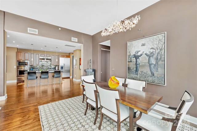 dining space featuring light wood-type flooring, sink, and a chandelier