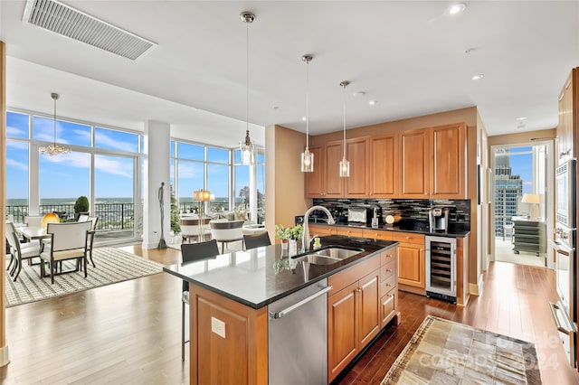 kitchen featuring dishwasher, hanging light fixtures, a kitchen island with sink, and sink