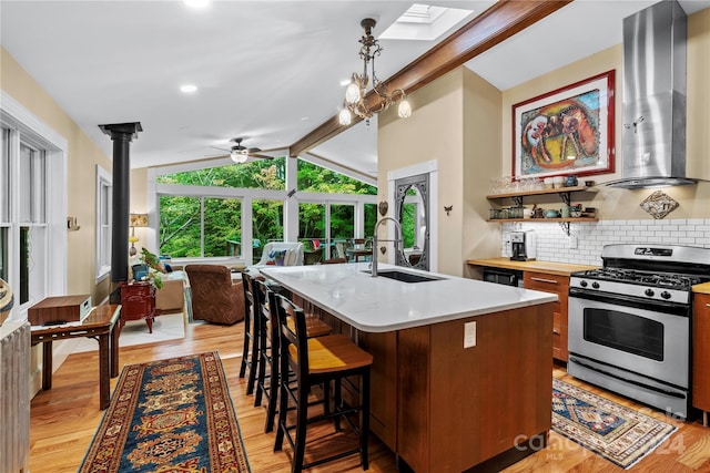 kitchen featuring light hardwood / wood-style floors, a center island with sink, gas range, sink, and range hood