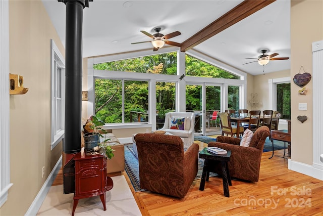 living room with lofted ceiling with beams, hardwood / wood-style floors, a wood stove, and ceiling fan