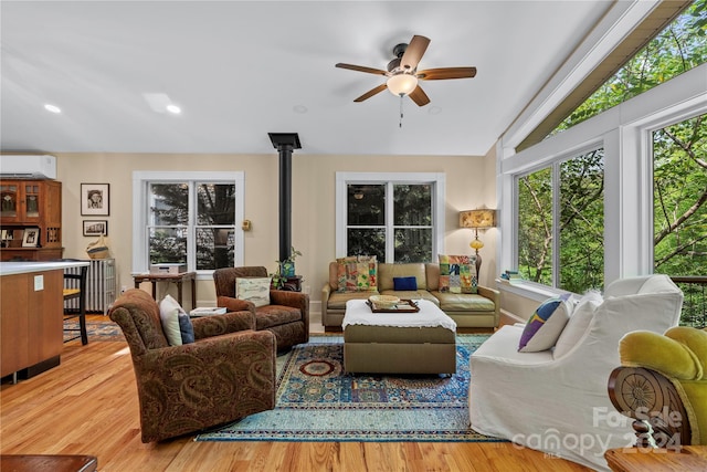 living room featuring a wall unit AC, a wood stove, lofted ceiling, and hardwood / wood-style flooring