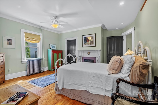 bedroom featuring ceiling fan, radiator heating unit, light hardwood / wood-style flooring, and crown molding