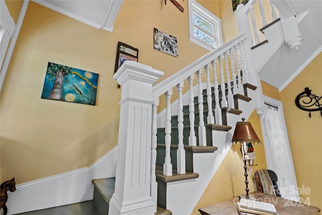 staircase featuring decorative columns and ornamental molding