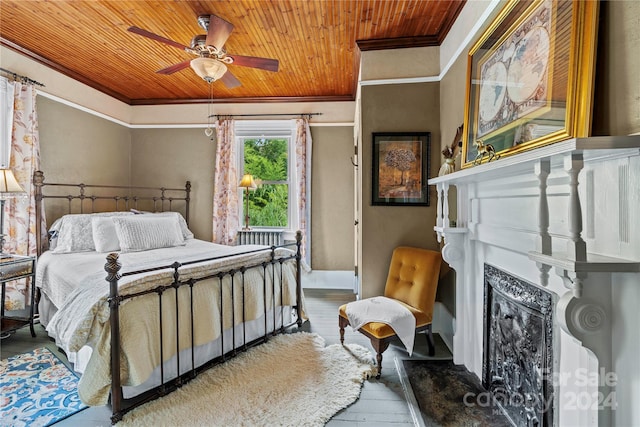 bedroom with hardwood / wood-style floors, wooden ceiling, ornamental molding, ceiling fan, and a fireplace