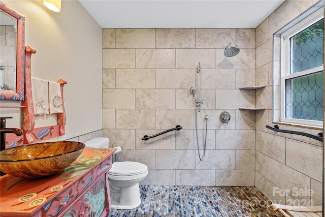 bathroom featuring toilet, vanity, tile patterned floors, and tiled shower