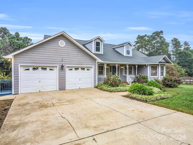 cape cod-style house featuring a garage, a front lawn, and covered porch