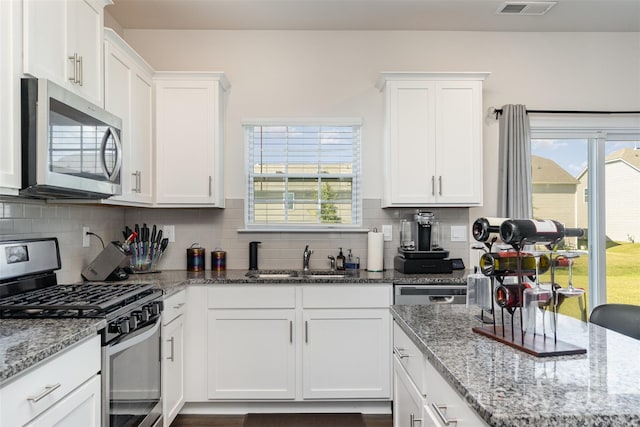 kitchen with white cabinets, stainless steel appliances, sink, and decorative backsplash