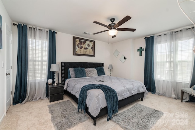 carpeted bedroom with multiple windows and ceiling fan