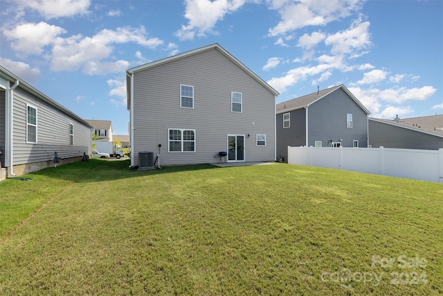 rear view of property featuring cooling unit and a yard