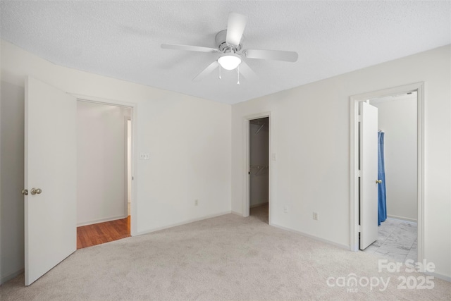 unfurnished bedroom with a walk in closet, light carpet, and a textured ceiling