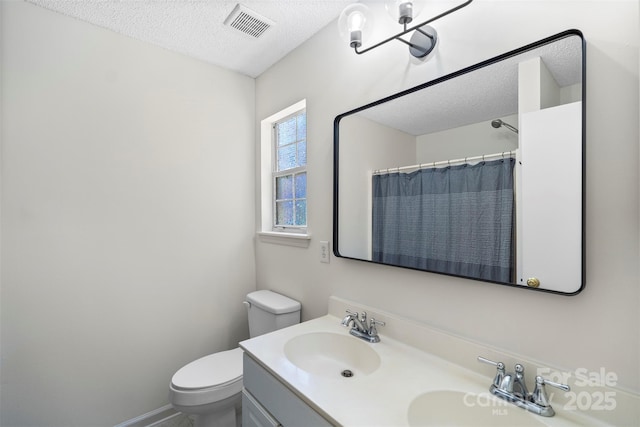 bathroom featuring vanity, curtained shower, toilet, and a textured ceiling