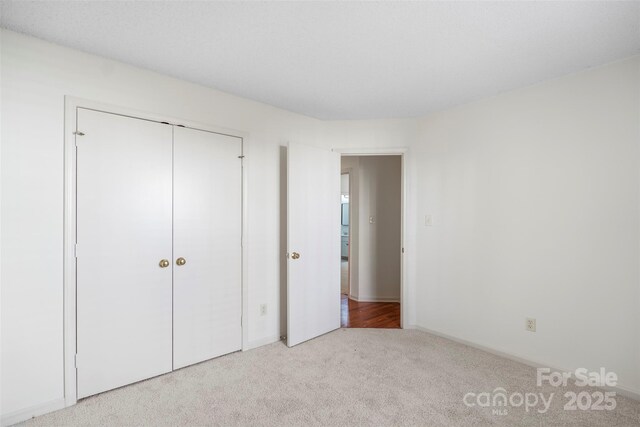 unfurnished bedroom featuring light carpet and a closet