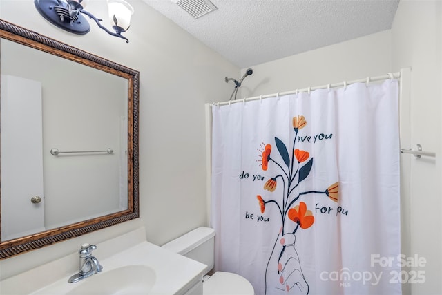 bathroom with a shower with curtain, vanity, a textured ceiling, and toilet