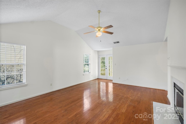 unfurnished living room with hardwood / wood-style flooring, vaulted ceiling, french doors, and ceiling fan