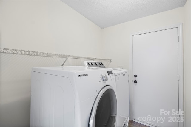 laundry room featuring washing machine and clothes dryer and a textured ceiling