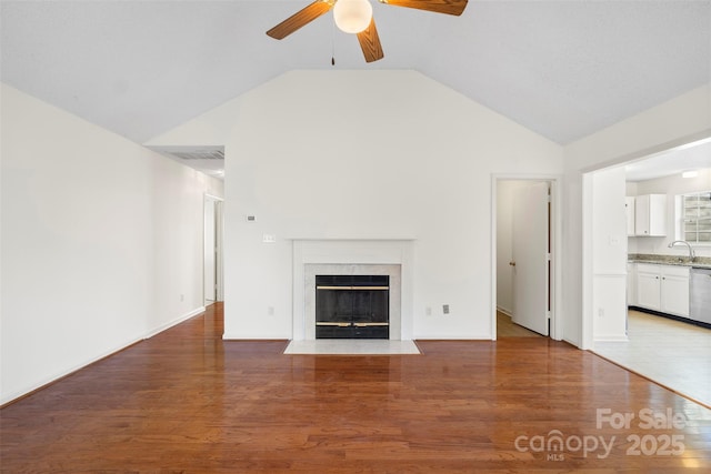 unfurnished living room featuring hardwood / wood-style flooring, vaulted ceiling, and a high end fireplace