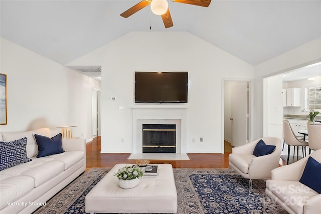 living room featuring lofted ceiling, hardwood / wood-style flooring, a fireplace, and ceiling fan