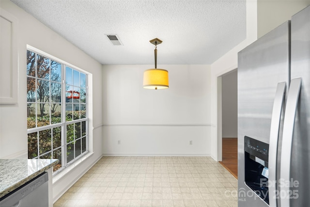 unfurnished dining area featuring a textured ceiling