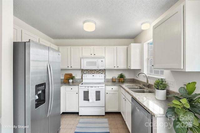 kitchen featuring sink, white cabinets, decorative backsplash, stainless steel appliances, and light stone countertops