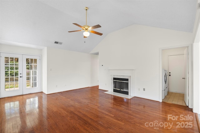 unfurnished living room featuring french doors, high vaulted ceiling, hardwood / wood-style floors, ceiling fan, and washing machine and dryer