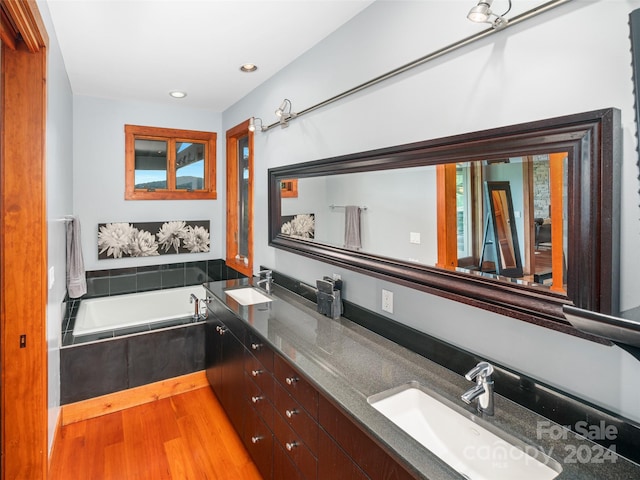 bathroom featuring tiled tub, vanity, and hardwood / wood-style floors