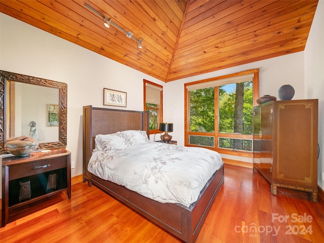 bedroom featuring light hardwood / wood-style flooring, vaulted ceiling, wooden ceiling, and rail lighting