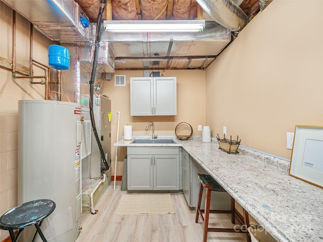 interior space with water heater, light hardwood / wood-style flooring, and sink