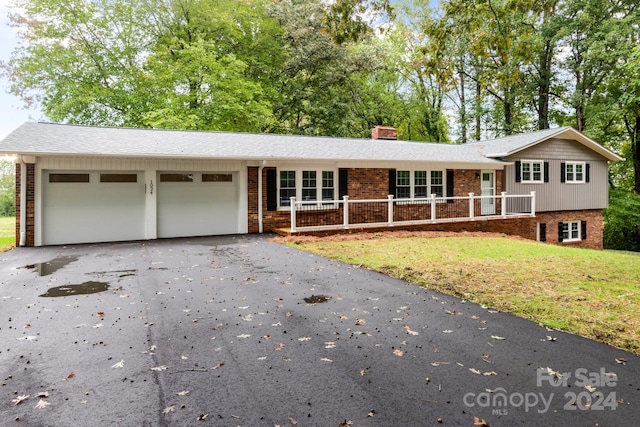 view of front of house with a garage, a front yard, and covered porch