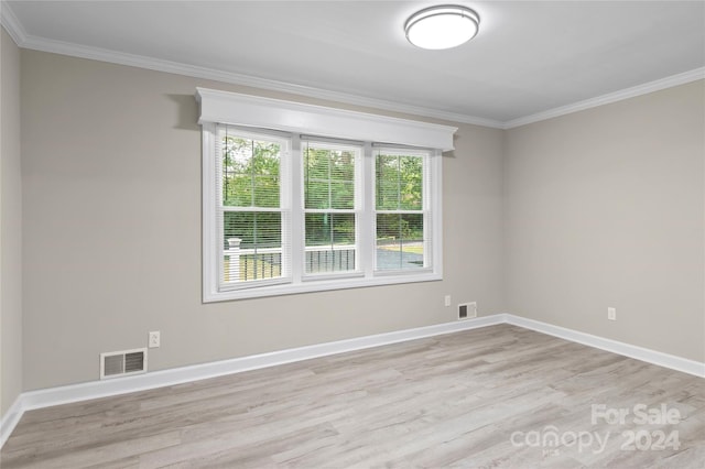 spare room with ornamental molding and light wood-type flooring