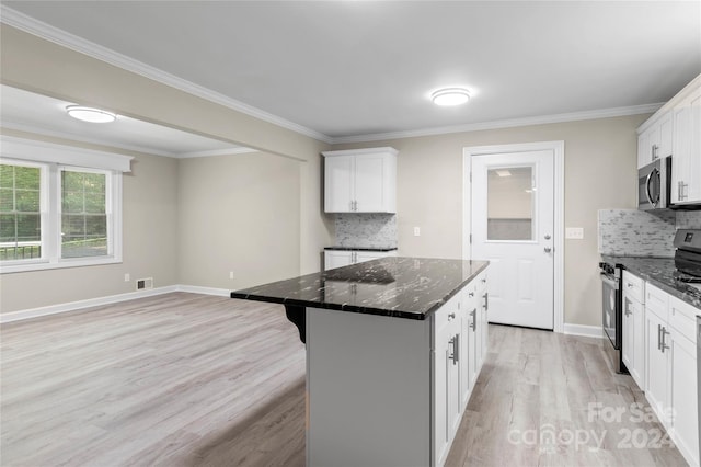 kitchen featuring dark stone counters, tasteful backsplash, white cabinetry, a kitchen island, and appliances with stainless steel finishes