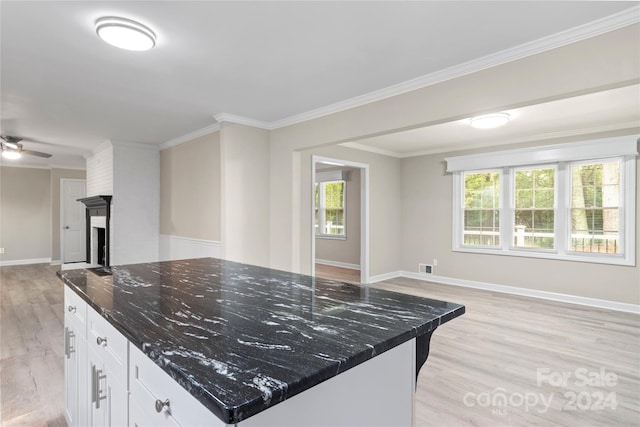 kitchen with dark stone counters, a center island, white cabinets, light hardwood / wood-style flooring, and ceiling fan