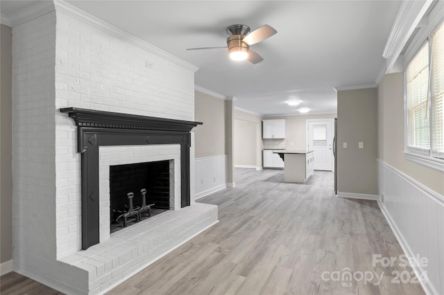 unfurnished living room with ornamental molding, light wood-type flooring, ceiling fan, and a fireplace