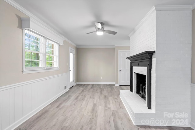 unfurnished living room featuring light hardwood / wood-style flooring, a brick fireplace, ceiling fan, and crown molding