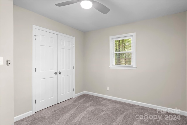 unfurnished bedroom featuring carpet, ceiling fan, and a closet