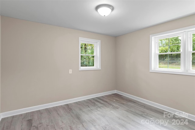 empty room with light hardwood / wood-style floors and plenty of natural light