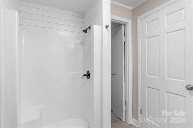 bathroom with washtub / shower combination and hardwood / wood-style flooring