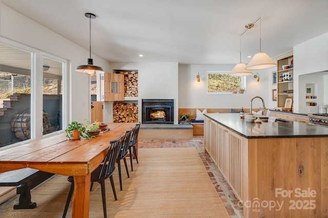 22 Kenilwood Pl, Asheville, NC 28803 - kitchen featuring a sink, a lit fireplace, dark countertops, a center island with sink, and pendant lighting