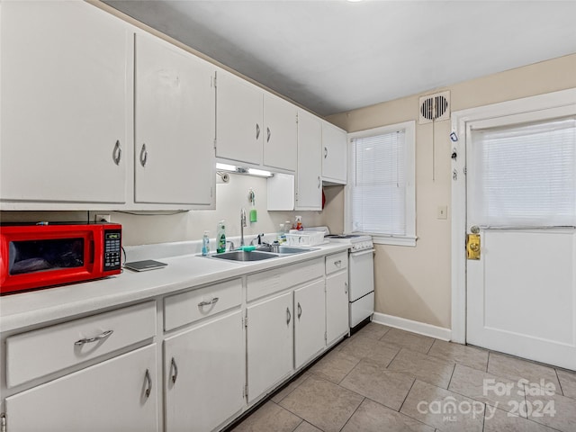 kitchen with light tile patterned flooring, white cabinets, sink, and white range