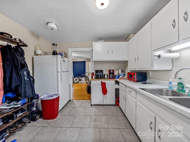 kitchen with white cabinetry, sink, and white refrigerator