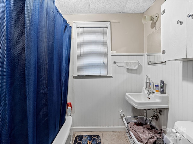 full bathroom with tile patterned floors, toilet, sink, a paneled ceiling, and shower / bathtub combination with curtain