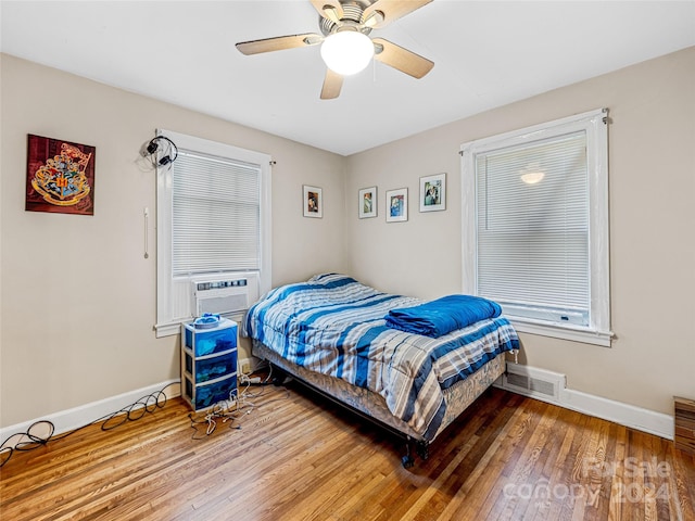 bedroom with cooling unit, wood-type flooring, and ceiling fan