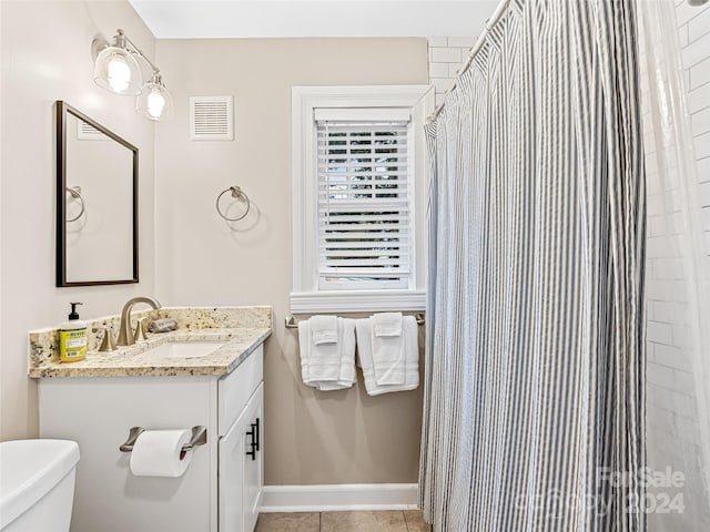 bathroom featuring vanity, toilet, walk in shower, and tile patterned flooring