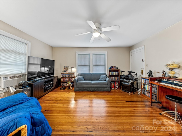 living room with ceiling fan, cooling unit, and light hardwood / wood-style flooring