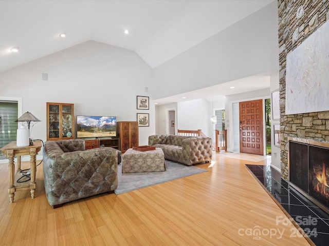 living room featuring light wood-type flooring, a fireplace, and high vaulted ceiling