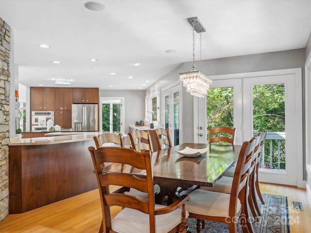 dining space featuring plenty of natural light, french doors, a chandelier, and light hardwood / wood-style flooring