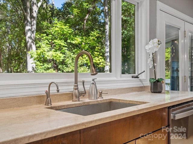 kitchen featuring sink, stainless steel dishwasher, and light stone counters